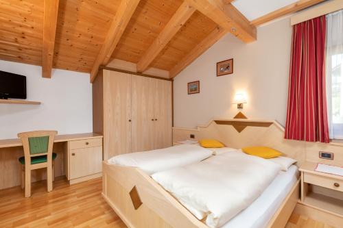 a bedroom with a large bed and a desk at Ciasa Odlana in San Cassiano