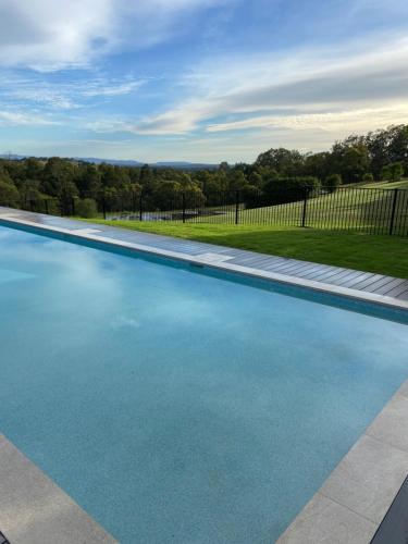 a swimming pool with blue water in a yard at Wine Country Villas in Pokolbin