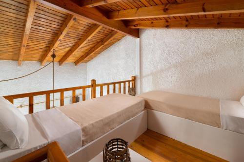 two beds in a room with wooden ceilings at Elefteria Apts & Suites in Kolimbia