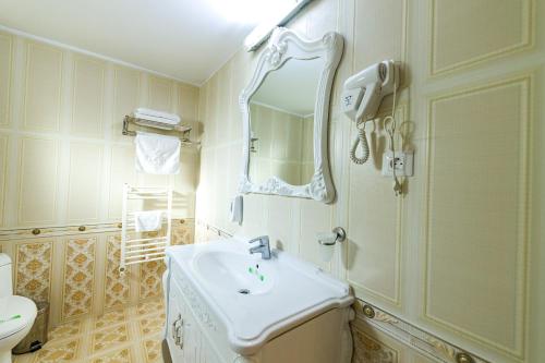 Hotel Helin Central في كرايوفا: حمام أبيض مع حوض ومرآة