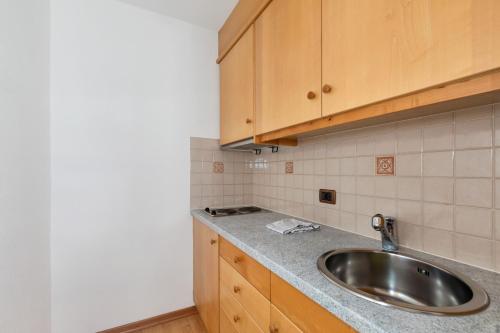 a kitchen with a sink and wooden cabinets at Apartments Puntin in San Cassiano