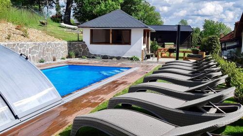 a row of lounge chairs next to a swimming pool at EDER- Penzion & Apartmány in Horní Planá
