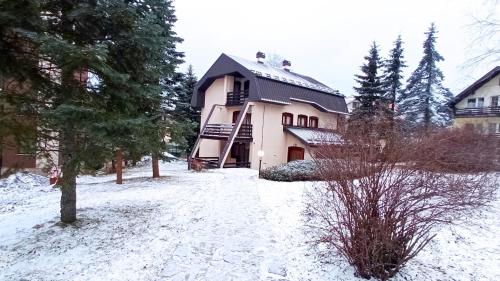a house with a snow covered yard in front of it at Konačište Zlatibor in Zlatibor