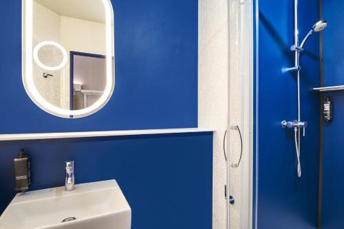 a blue bathroom with a sink and a mirror at ibis Clamart Paris Velizy in Clamart