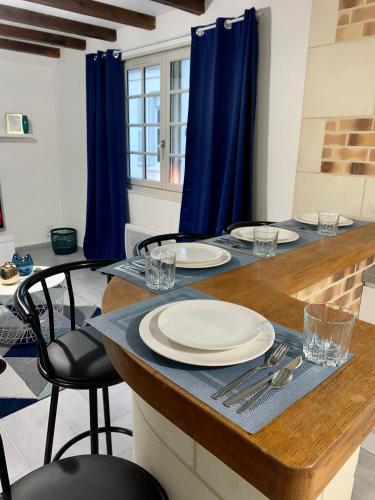 une table avec des assiettes et de l'argenterie au-dessus dans l'établissement Appartement les Bleuets - Centre ville de Saumur, à Saumur