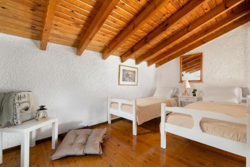 a bedroom with two beds and a wooden ceiling at Elefteria Apts & Suites in Kolimbia