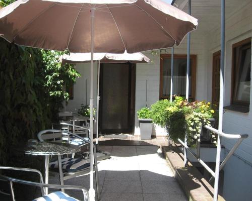 un patio con sombrilla, mesas y sillas en Altes Schulhaus, en Bad Schwartau