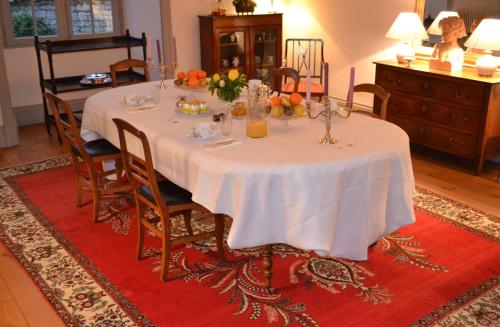 un tavolo da pranzo con una tovaglia bianca e sedie di Le Petit Logis a Rouillac