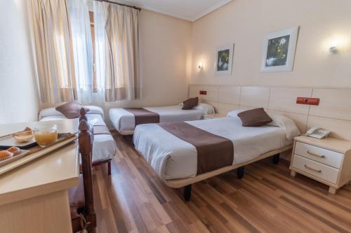 a hotel room with two beds and a desk at Hostal Rural El Caño by Vivere Stays in Alpedrete