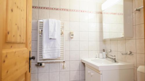 Baño blanco con lavabo y espejo en Wunderstay Alpine 16 Chic Studio Central Location en Klosters Serneus