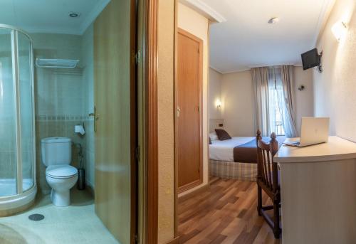 1 dormitorio con 1 cama y baño con aseo. en Hostal Rural El Caño by Vivere Stays en Alpedrete