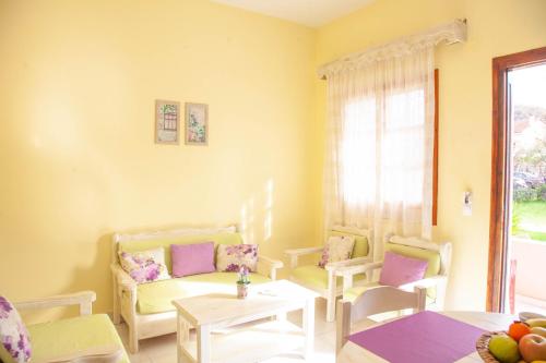 een woonkamer met stoelen, een tafel en een raam bij Dalia Apartment in Almiros strand