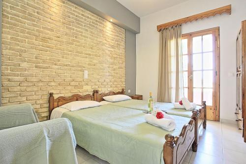 a bedroom with two beds and a brick wall at Dalia Apartment in Almiros Beach