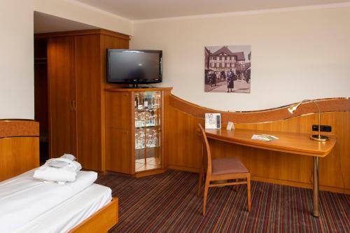 a hotel room with a desk and a tv at Ringhotel Katharinen Hof in Unna