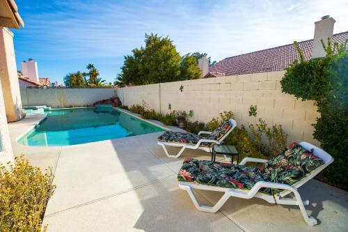 2 chaises longues et une piscine dans l'arrière-cour dans l'établissement Luxury 1900 SQ FT House Huge 46 FT Pool & Hot SPA, à Las Vegas