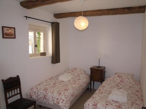 une chambre avec deux lits et une chaise et une fenêtre dans l'établissement Gîtes Les Neuf Cerisiers, à Mascaras