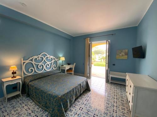 um quarto com uma cama e uma porta para um pátio em Hotel Bougainville em Lipari