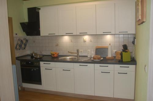 a kitchen with white cabinets and a sink at Ferienhaus Waldblick in Siegmundsburg