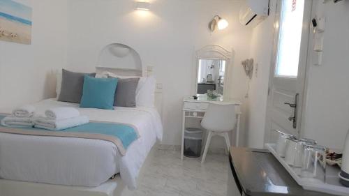 a white bedroom with a bed and a desk at Kafieris View in Firostefani
