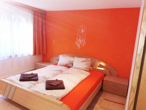 Cama en habitación con pared de color naranja en Haus Falke en Saas-Grund