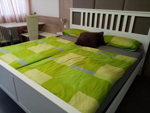a bed with a green and yellow blanket on it at modern Hoteliving Gießen in Gießen