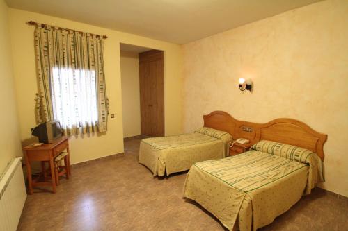 una camera d'albergo con due letti e una televisione di Hostal Restaurante Cuatro Caminos a Calera y Chozas