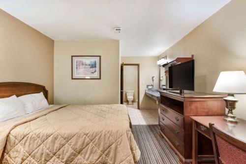 a hotel room with a bed and a desk and a television at Rodeway Inn Columbus West in Columbus