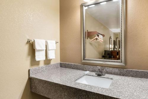 y baño con lavabo, espejo y toallas. en Rodeway Inn, en Columbus