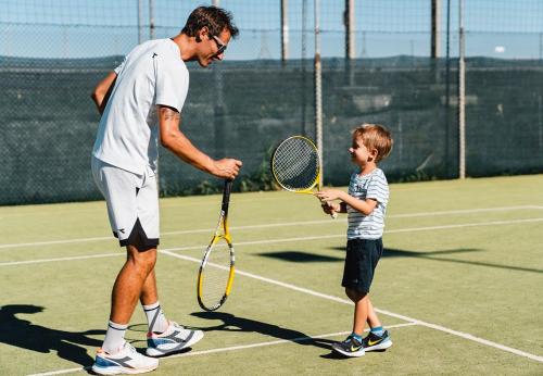 a man and a young boy holding a tennis racket at Natural Village Resort in Porto Potenza Picena