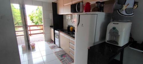 a kitchen with a white refrigerator and a window at Promessa divina Carneiros in Tamandaré