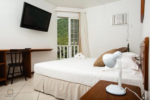 a bedroom with a white bed and a television at Ilha Náutica in Florianópolis