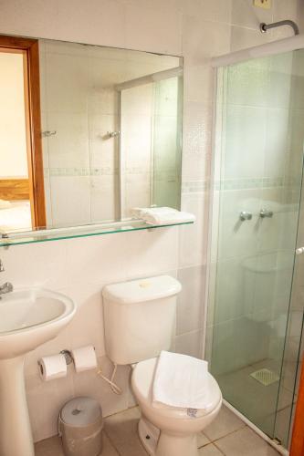 a bathroom with a toilet and a glass shower at Pousada Pescador in Ubatuba
