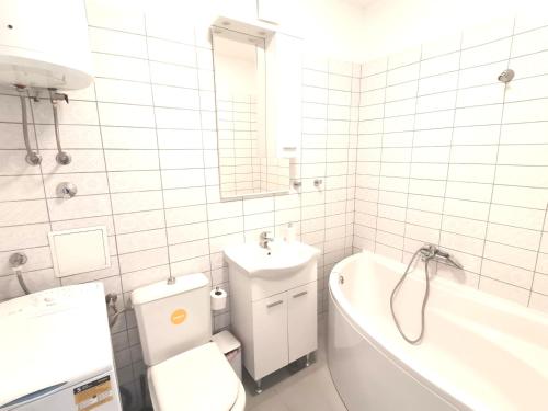 a white bathroom with a toilet and a tub and a sink at Residential apartment in Split