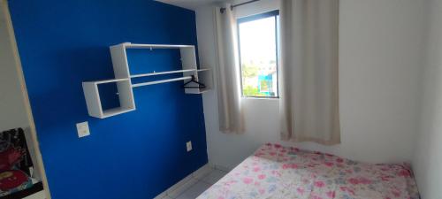 a blue room with a bed and a window at Promessa divina Carneiros in Tamandaré
