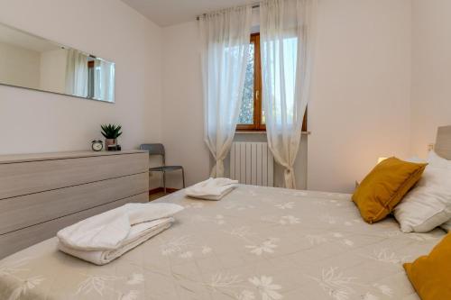 una camera bianca con un grande letto con cuscini gialli di Felicity a Toscolano Maderno