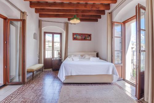 a bedroom with a white bed in a room with windows at Ático Al Andalus in Tarifa