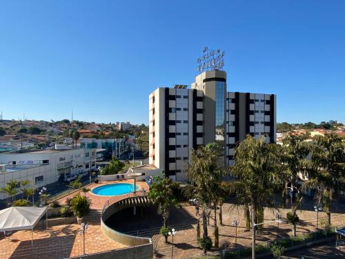 a view of a building with a pool and trees at HD Plaza Hotel in Assis