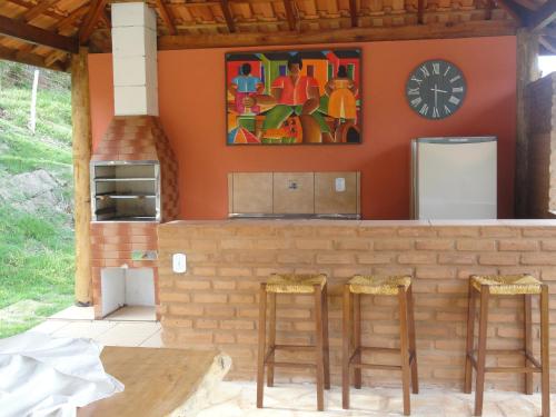 a bar with two stools and a clock on the wall at Pousada Sonho Meu in Itanhandu