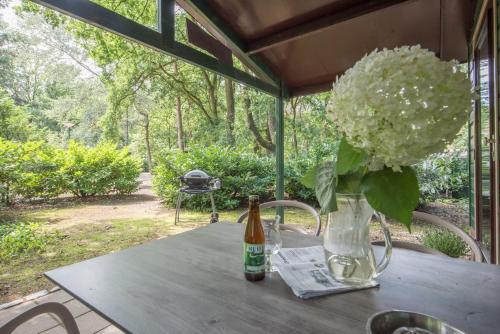 a table with a vase of flowers and a bottle of beer at Vakantiepark Zevenbergen in Heesch
