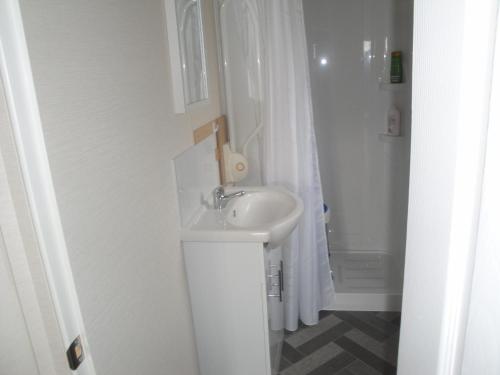 uma casa de banho branca com um lavatório e um chuveiro em NV 1219 - Beach Resort Nieuwvliet Bad em Nieuwvliet