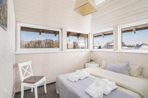 2 camas en una habitación con ventanas y silla en Vila 9Vėjai, en Girniki