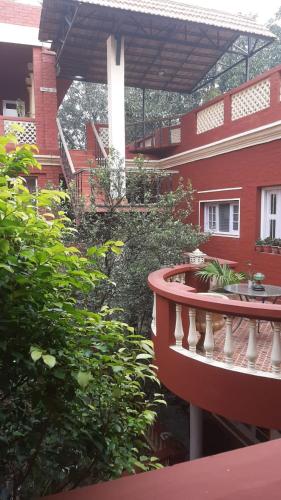 a balcony of a red building with bushes and trees at Ranjit's Svaasa Amritsar in Amritsar