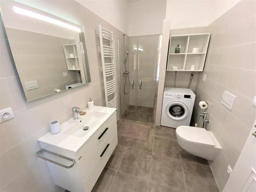 biała łazienka z umywalką i pralką w obiekcie Apartments Magnolia w Mariańskich Łaźniach