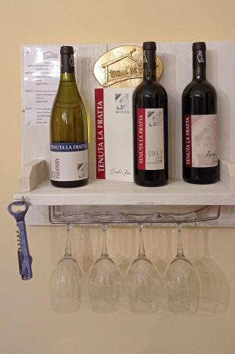 three bottles of wine on a shelf with wine glasses at Agriturismo Tenuta La Fratta in Bagni di Lucca