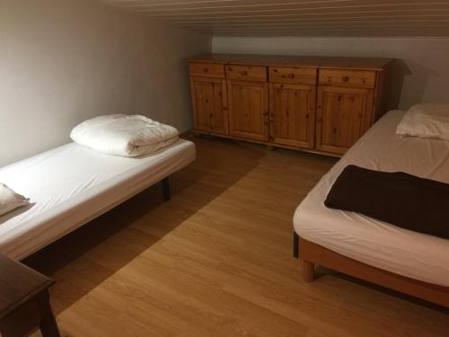 une chambre avec deux lits et une armoire en bois dans l'établissement Albizia, à Saint-Julien-des-Landes