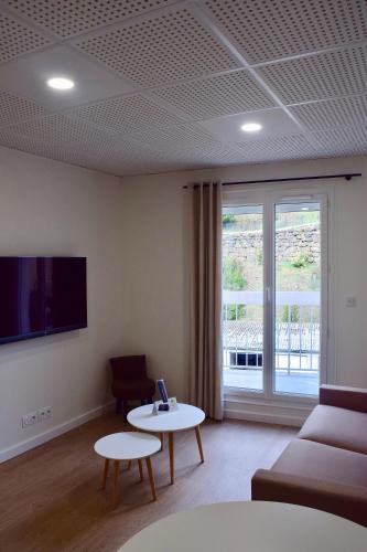 a living room with a couch and a table and a window at Hôtel et appartements les platanes in Thueyts