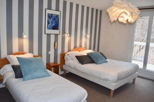 a bedroom with two beds and a chandelier at Hôtel et appartements les platanes in Thueyts