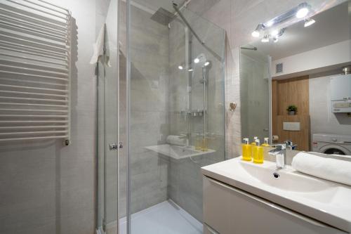 a bathroom with a shower and a sink and a glass shower stall at RentPlanet - Apartamenty Pstrowskiego in Szklarska Poręba