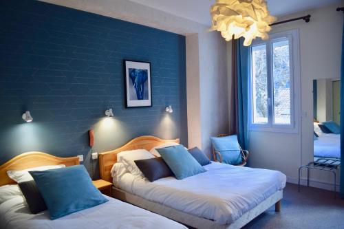 ein Schlafzimmer mit 2 Betten und einer blauen Wand in der Unterkunft Hôtel et appartements les platanes in Thueyts