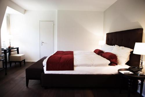 a bedroom with a large bed with white and red sheets at Hotel Schloss Hünigen in Konolfingen